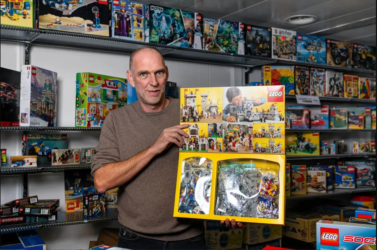 Ein Mann zeigt eine Schachtel voller Lego.